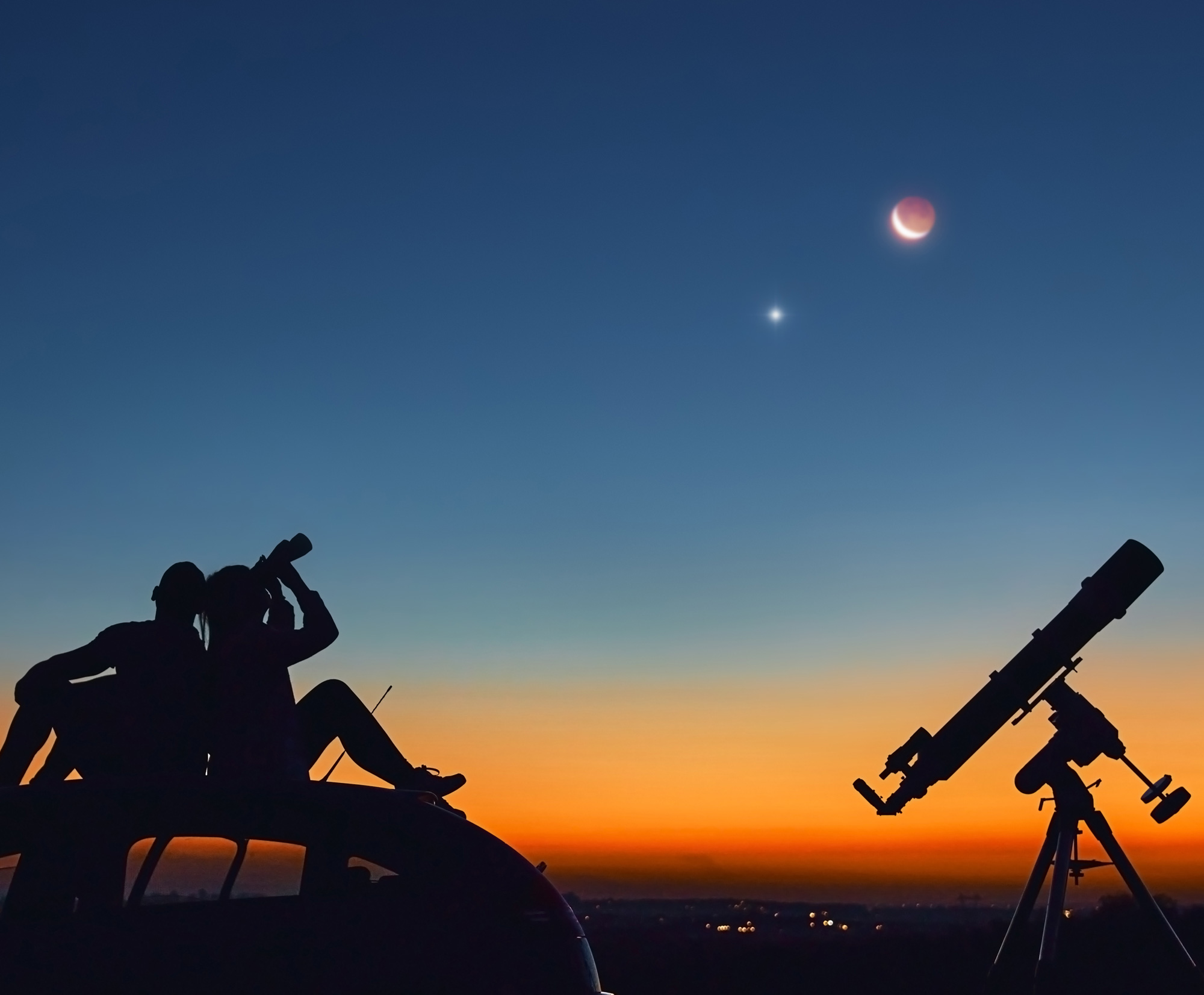 Two people viewing the stars and a telescope