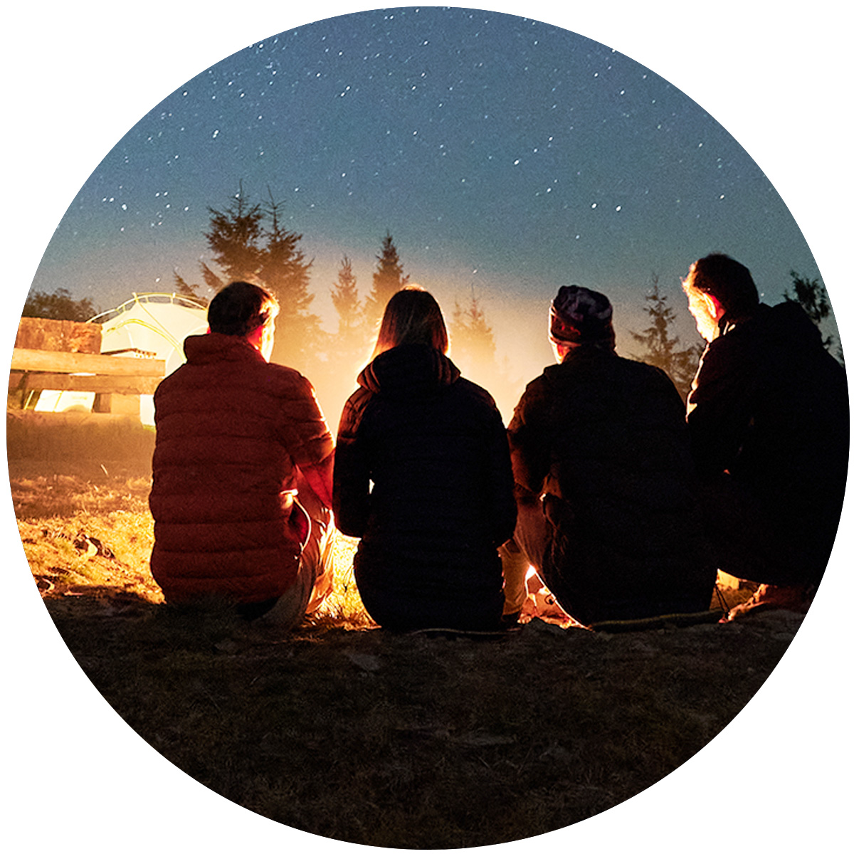 Four people sitting at a campfire